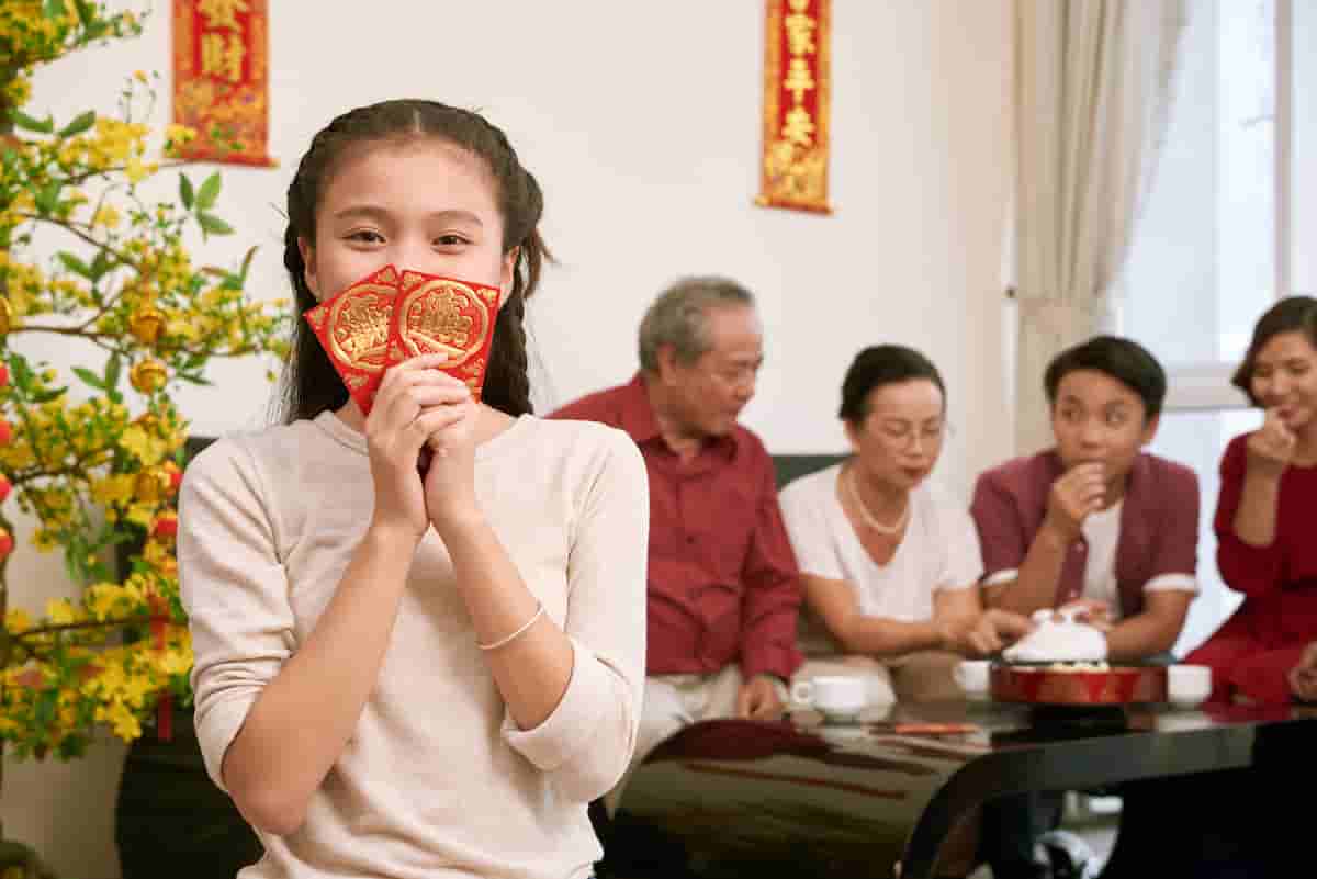 Chinese girl holding red packets with family in the background